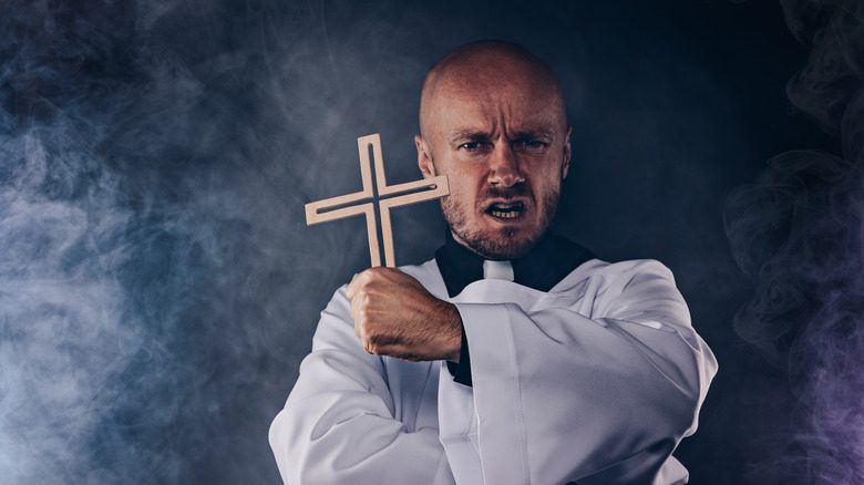 Католический священник держит крест