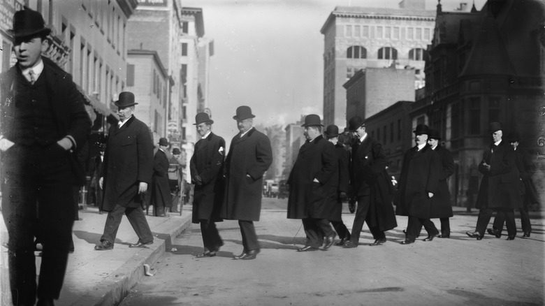 черно-белая фотография присяжных на процессе по делу Тоу, идущих через дорогу друг за другом в шинелях и шляпах-котелках
