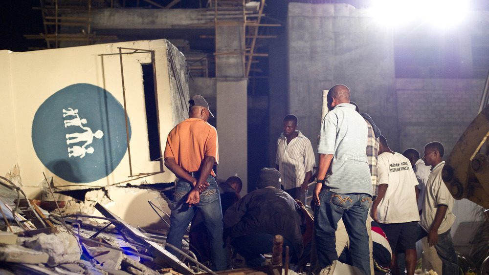 13 ЯНВАРЯ: Люди ищут выживших среди руин детской больницы после сильного землетрясения 13 января 2010 года в Порт-о-Пренсе, Гаити. 