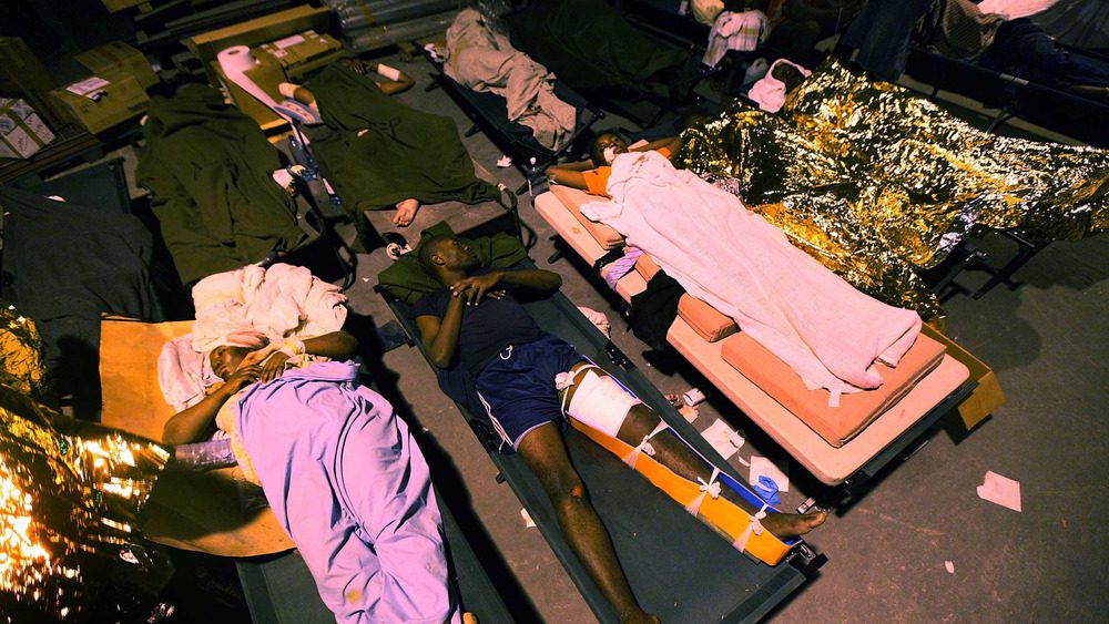 13 ЯНВАРЯ: Раненые люди в импровизированном полевом госпитале 13 января 2010 года в Порт-о-Пренсе, Гаити. 