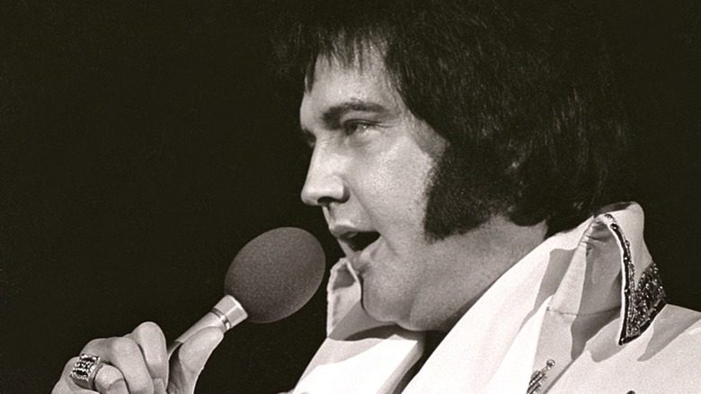 Элвис держит микрофон в 1977 году