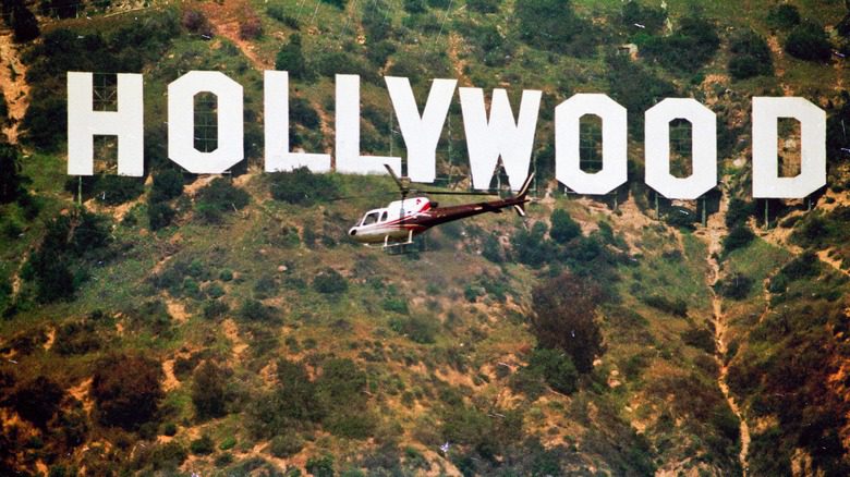 Вертолет пролетает над знаком Голливуда