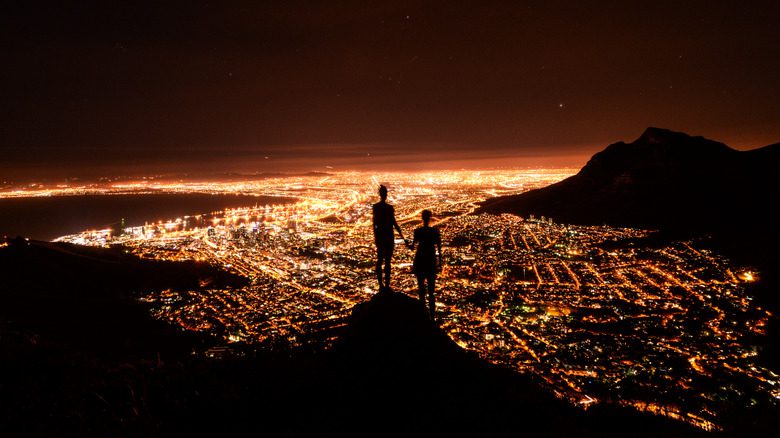 Силуэты людей, держащихся за руки, с видом на Кейптаун, Южная Африка.