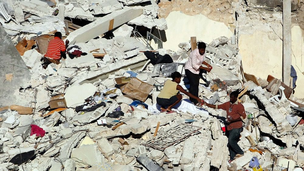 Люди копаются в обломках своего дома после сильного землетрясения, разрушившего его 14 января 2010 года в Порт-о-Пренсе, Гаити.