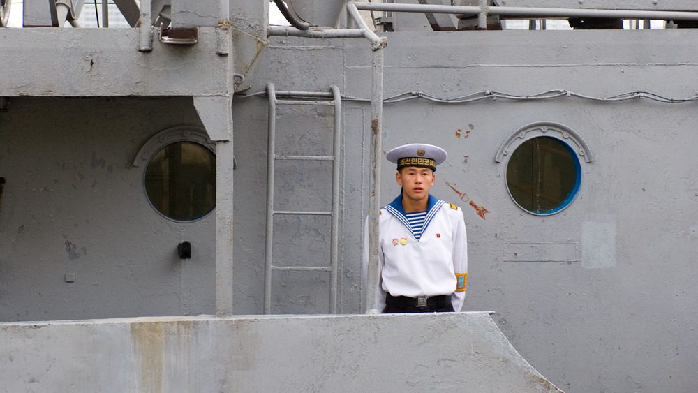 Северокорейский моряк стоит на вершине корабля ВМС США 