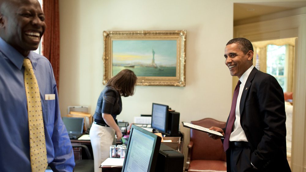 Президент Барак Обама смеется со своим помощником Реджи Лавом 