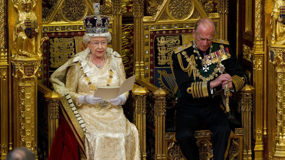 Принц Филипп, герцог Эдинбургский, слушает речь своей жены, королевы Великобритании Елизаветы II, выступающей в Палате лордов во время Государственного открытия парламента в Вестминстерском дворце перед Государственным открытием парламента 25 мая 2010 года в Лондоне, Англия.