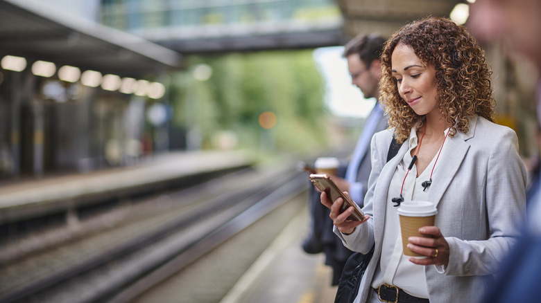 женщина с мобильным телефоном в ожидании поезда