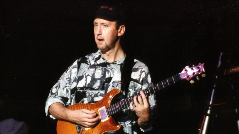 Ян Бэрнсон в кепке играет на гитаре на сцене
