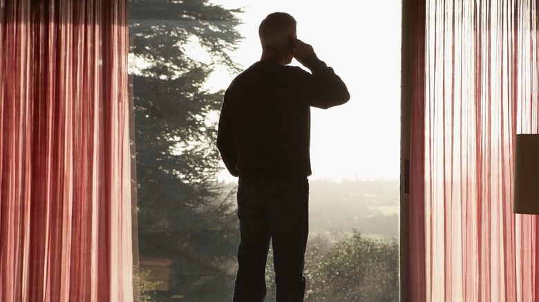Мужчина, делающий звонок, смотрит в окно