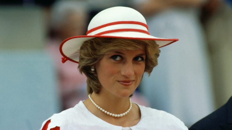 Принцесса Диана в белой красной шляпе улыбается на улице