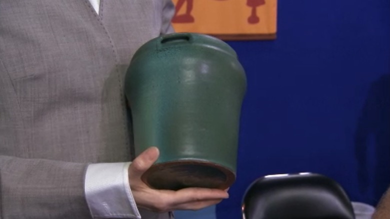 руки держат зеленую керамическую вазу