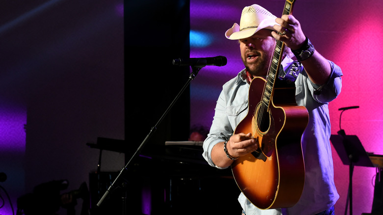 Тоби Кит в белой шляпе играет на гитаре на сцене
